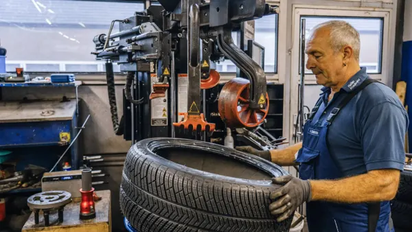 Mechaniker legt einen Reifen in die Montiermaschine